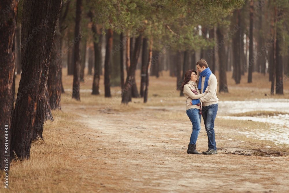 couple in winter play in snow and hugging near the pine. Two lovers with a toy bear. Valentine's Day  for couple in rustic style. Winter lovestory. Casual outfit with Blue accessories