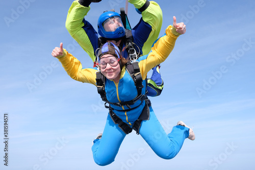 Skydiving. Tandem jump. Happy girl and her instructor are falling in the blue sky.
