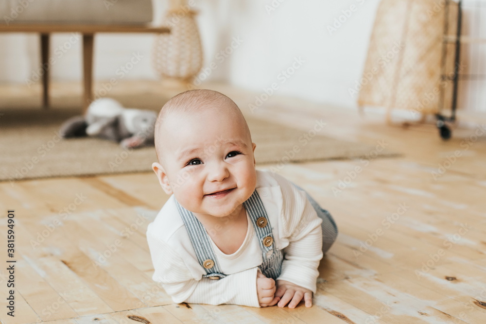 baby is lying on the floor. smiling six month old baby in a beautiful interior.sly kid baby is lying on the floor. smiling six month old baby in a beautiful interior.sly kid