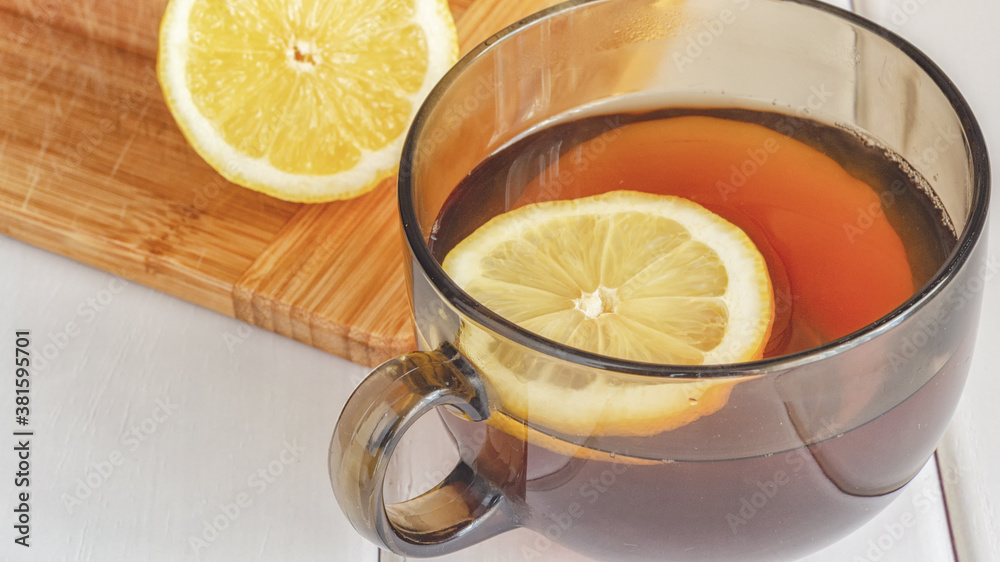 A cup of tea with lemon on a light wood table. ...