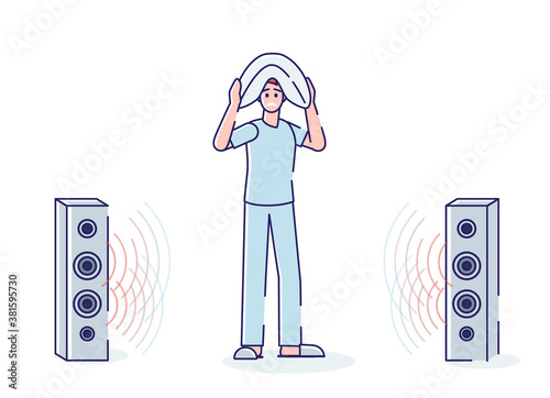 Sleepless man annoyed with loud music from loudspeakers hiding head under pillow
