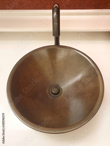 Round sinks and metal faucets are placed on a white granite countertop in a public restroom in a shopping mall.