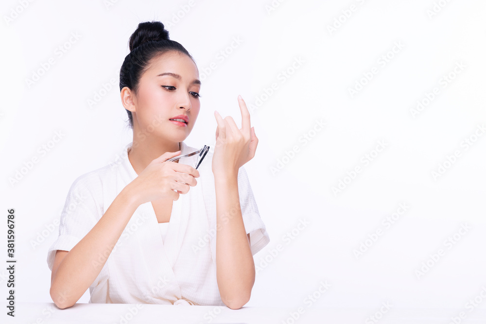 Beauty young woman doing manicure with cutting her fingernail while sitting over isolated white background with copy space. Healthy care concept. Beauty young woman doing manicure with cutting her fingernail while sitting over isolated white background with copy space. Healthy care concept.