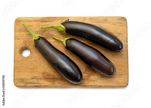 Three fresh eggplants on a wooden kitchen board on a white background. Before fitting a dietary vegetable dish.