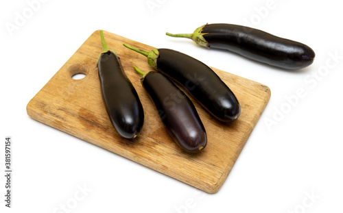 Four fresh eggplants on a wooden kitchen board on a white background. Free space for text or prices.