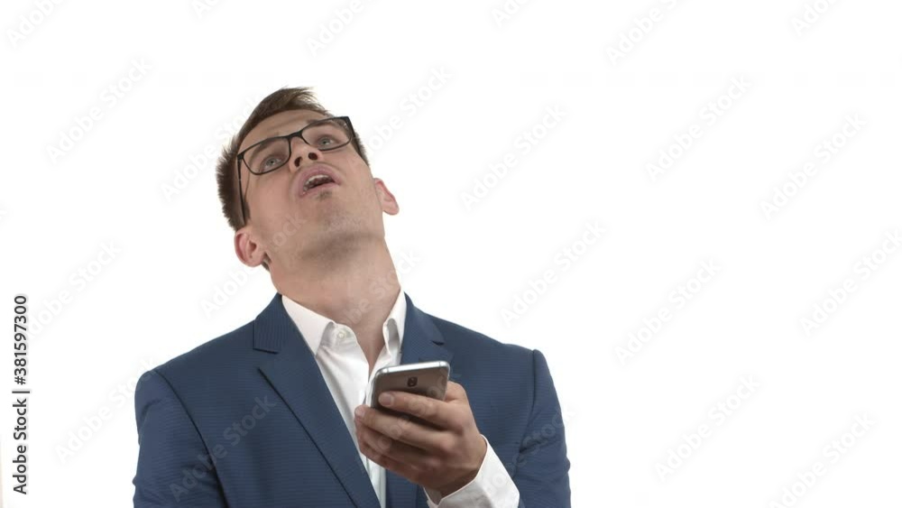 Close-up of handsome businessman with blond hair, wearing blue suit and glasses, looking at mobile phone screen, reading bad news and sighing, feeling disappointed about something bad Close-up of handsome businessman with blond hair, wearing blue suit and glasses, looking at mobile phone screen, reading bad news and sighing, feeling disappointed about something bad