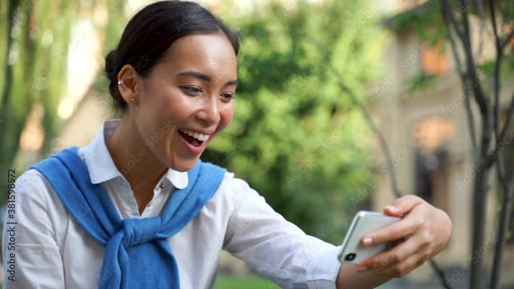 Cheerful asian woman having a video call outdoors. Cheerful asian woman having a video call outdoors.