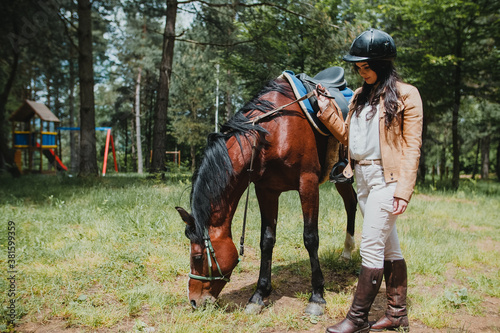Young beautiful girl stroking a brown horse.