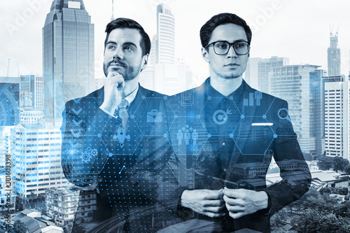 Two handsome businessman in suits thinking about career opportunities at research and development department at international consulting company. Hologram icons over Kuala Lumpur background. photo