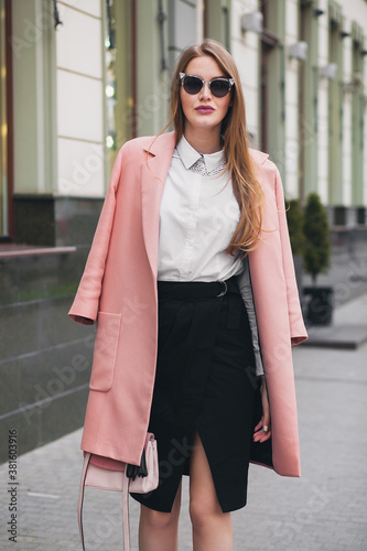 sexy young stylish beautiful woman walking in street, wearing pink coat, purse, sunglasses, white shirt, black skirt, fashion outfit, autumn trend, smiling happy, accessories