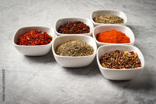 Spices in bowls on a gray concrete background.
