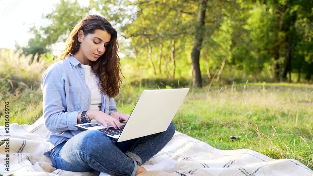Young adult girl student studying in nature in the park on the lawn using a laptop on a sunny summer day. Pretty and attractive female freelancer working at a distance online Distances. Relax and rest Young adult girl student studying in nature in the park on the lawn using a laptop on a sunny summer day. Pretty and attractive female freelancer working at a distance online Distances. Relax and rest
