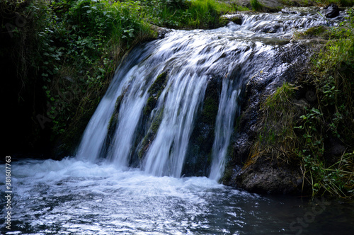 a rapid mountain stream turns into a small waterfall and flows into a lake