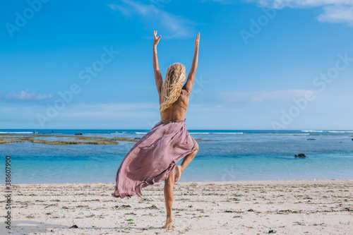Young woman practicing yoga on seaside