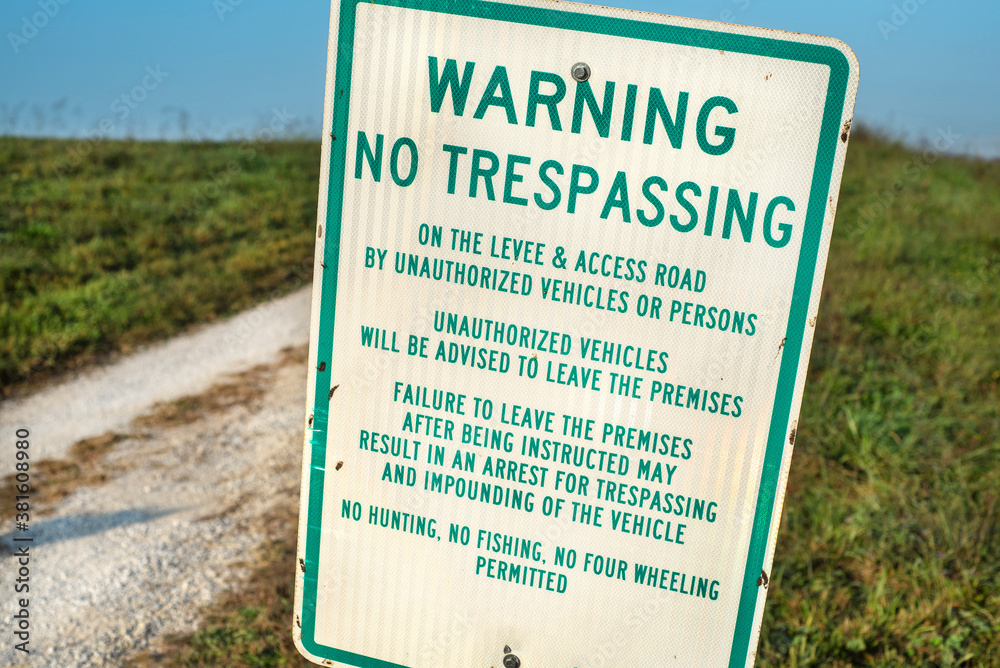 Warning no trespassing sign on gravel road in country Warning no trespassing sign on gravel road in country