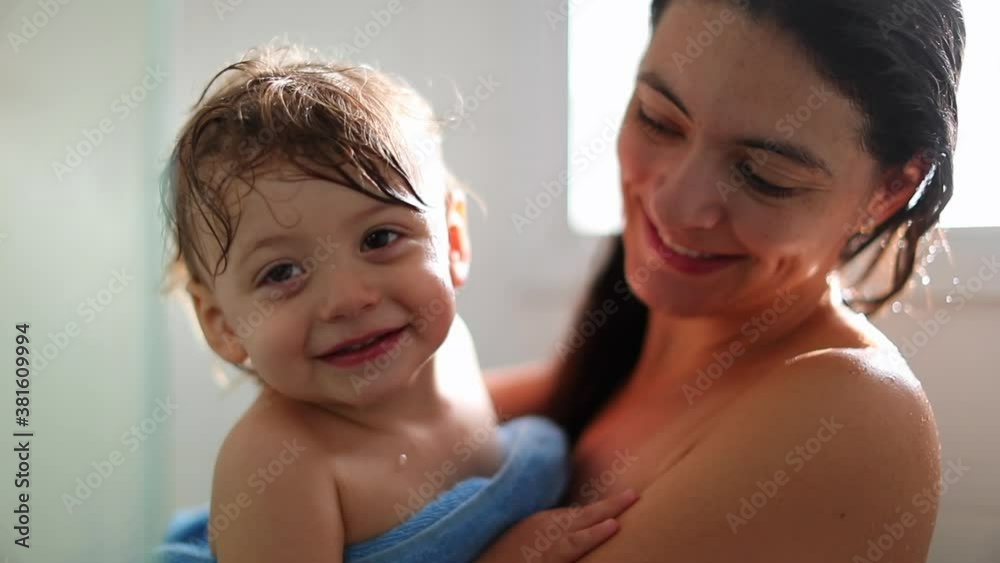 Mother holding smiling baby looking at camera wrapped in towel Mother holding smiling baby looking at camera wrapped in towel