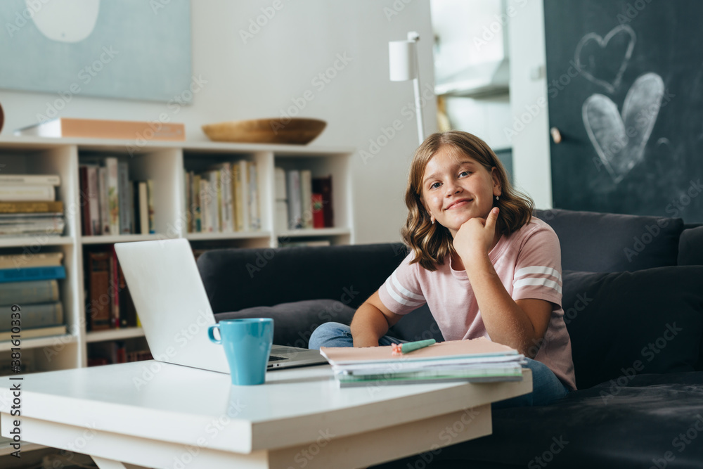 young girl sitting on sofa at her home and using computer for online education young girl sitting on sofa at her home and using computer for online education