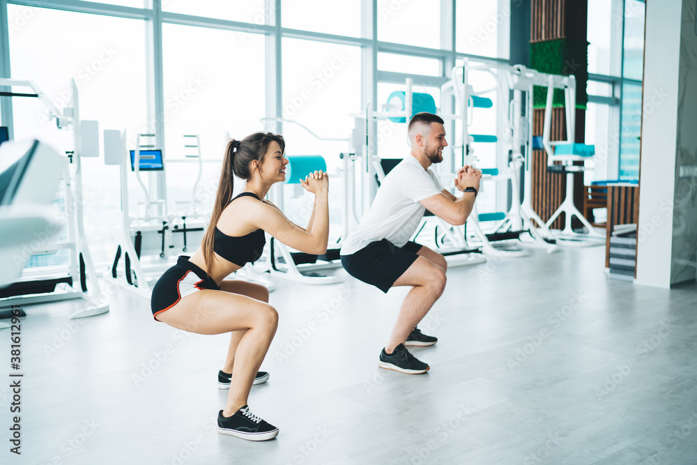 Cheerful sportspeople doing squat exercise Cheerful sportspeople doing squat exercise