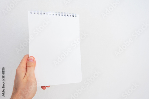 Person shows notebook, man's hand with white notebook, closeup, cropped image, copy space