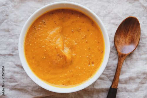 Hot spicy pumpkin soup in a bowl on white tablecloth background.