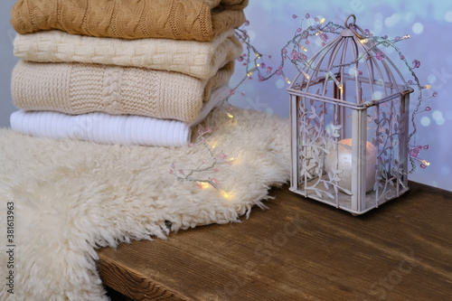 cozy Scandinavian hyugge, white candles, woolen clothes in a pile, sheepskin, halloween concept, cozy home, aromatherapy photo