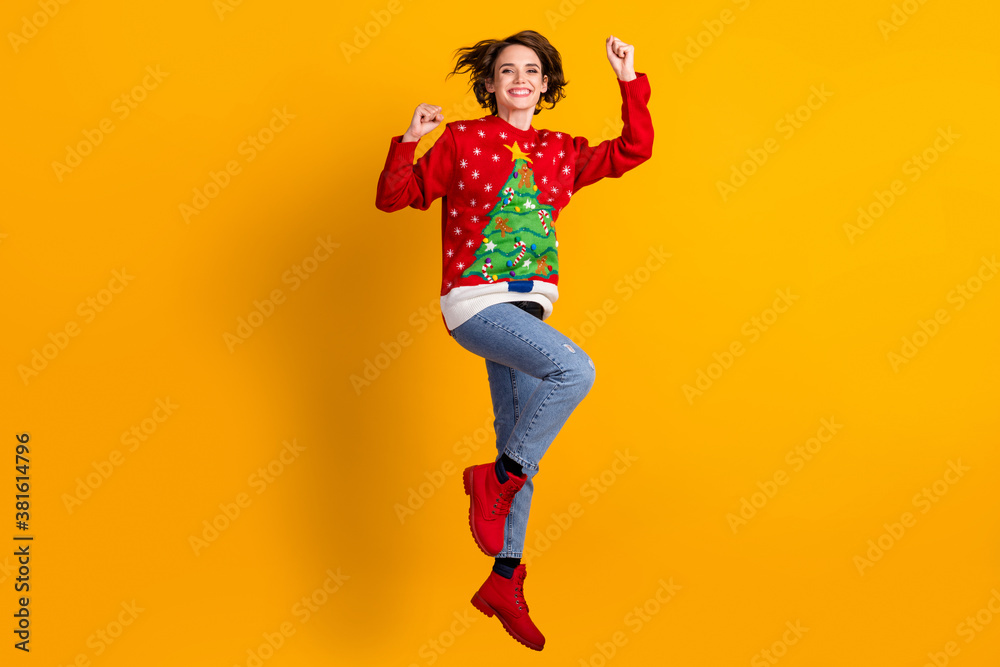 Full size photo of cheerful girl jump raise fists win x-mas eve time noel lottery wear christmas tree decor sweater pullover denim jeans isolated over bright shine color background Full size photo of cheerful girl jump raise fists win x-mas eve time noel lottery wear christmas tree decor sweater pullover denim jeans isolated over bright shine color background