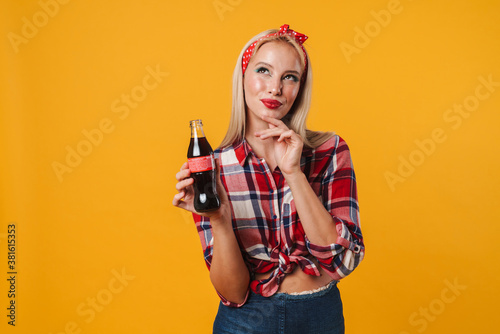 Image of pleased charming pinup girl posing with soda and thinking