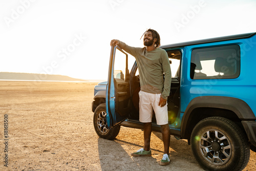 Image of joyful african american man smiling and travelling with car photo