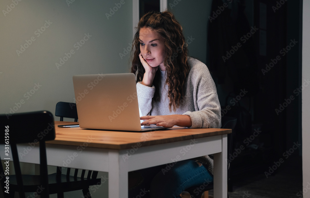 Woman working on laptop late at home stock photo