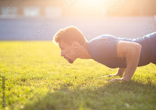 Athletic man doing push ups at the grass