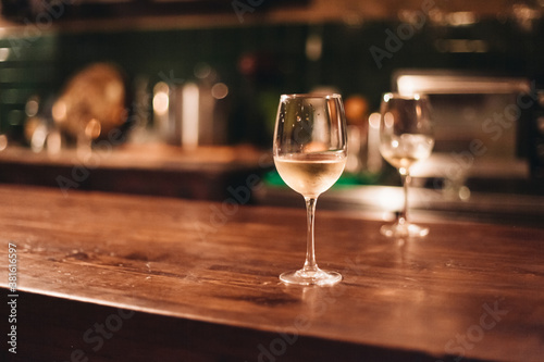 Two glasses of white wine on a wooden table in a cozy dark bar