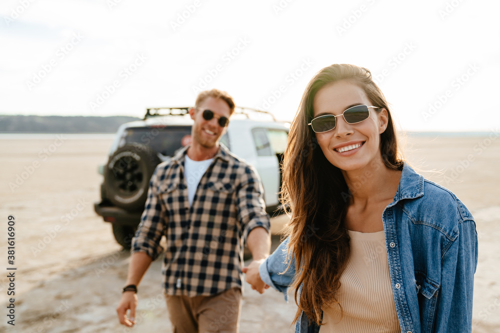 Young happy loving couple outdoors at beach near car walking