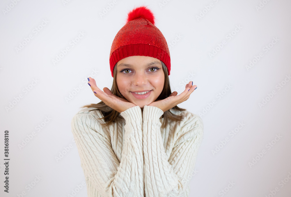 Pretty girl wearing red winter hat and sweater over white background, close up