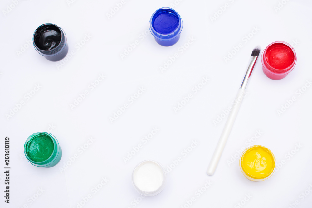 Bottles of different colors gouache paints and artist brush, white background, copy space