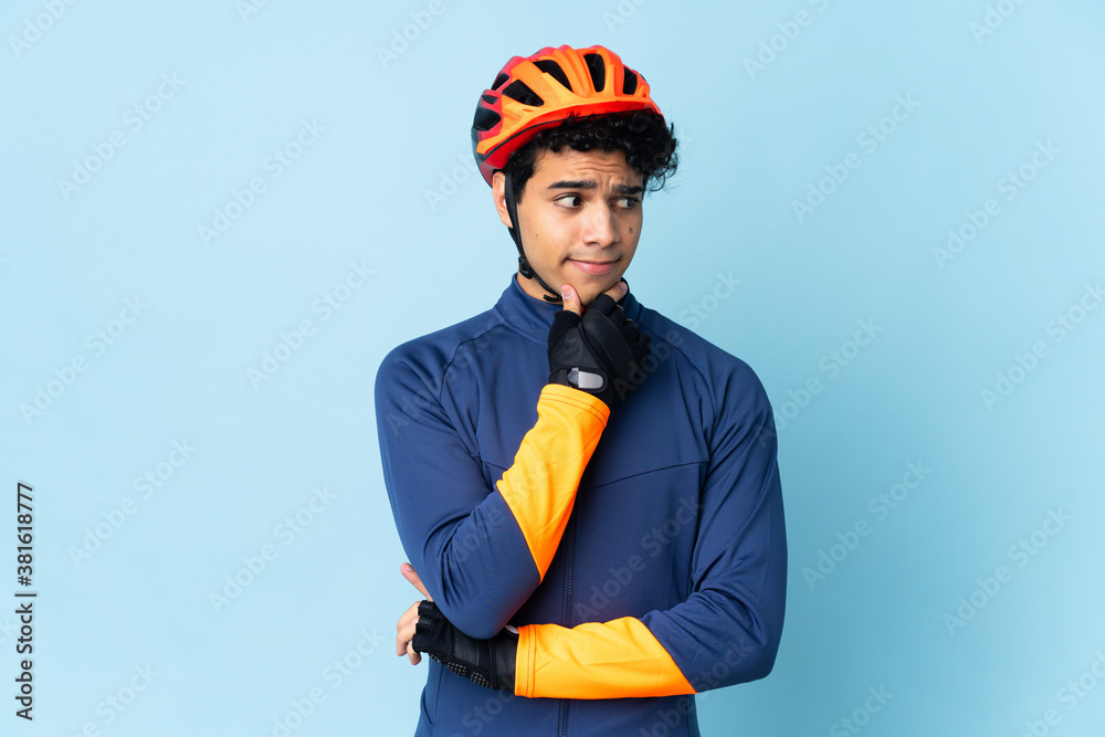 Venezuelan cyclist man isolated on blue background having doubts and thinking Venezuelan cyclist man isolated on blue background having doubts and thinking