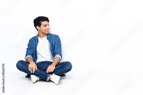 Venezuelan man sitting on the floor looking side © luismolinero