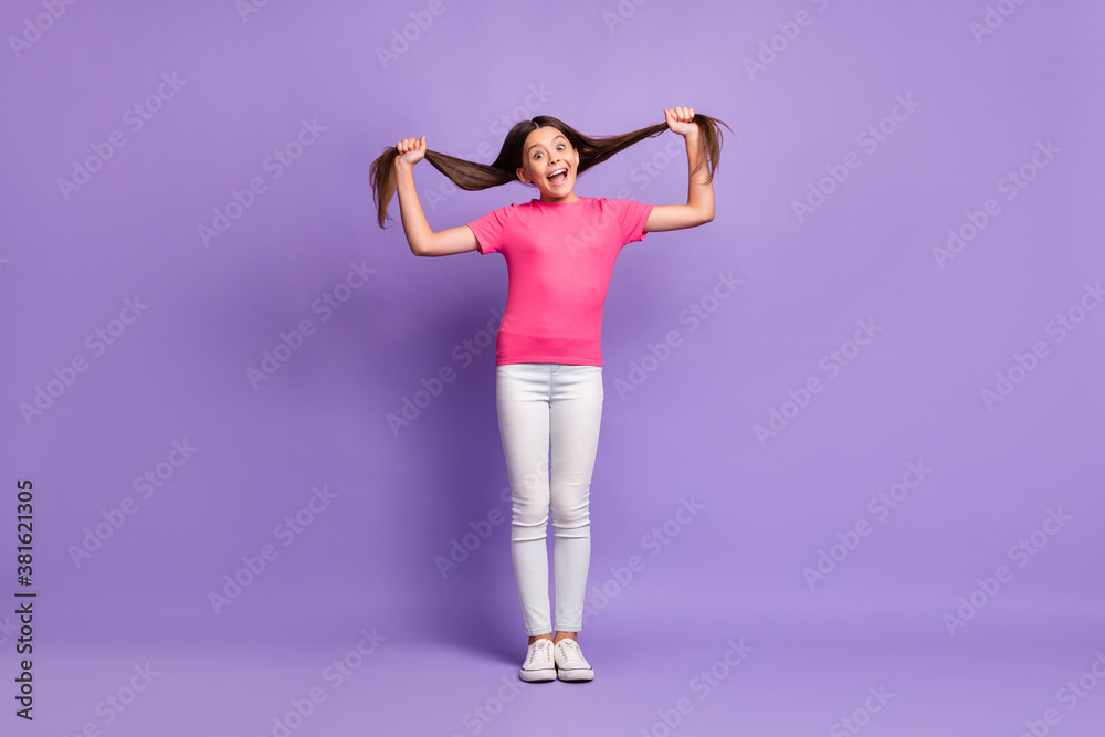 Full length body size photo of funny grimacing girl holding long brunette hair fooling isolated on purple color background Full length body size photo of funny grimacing girl holding long brunette hair fooling isolated on purple color background