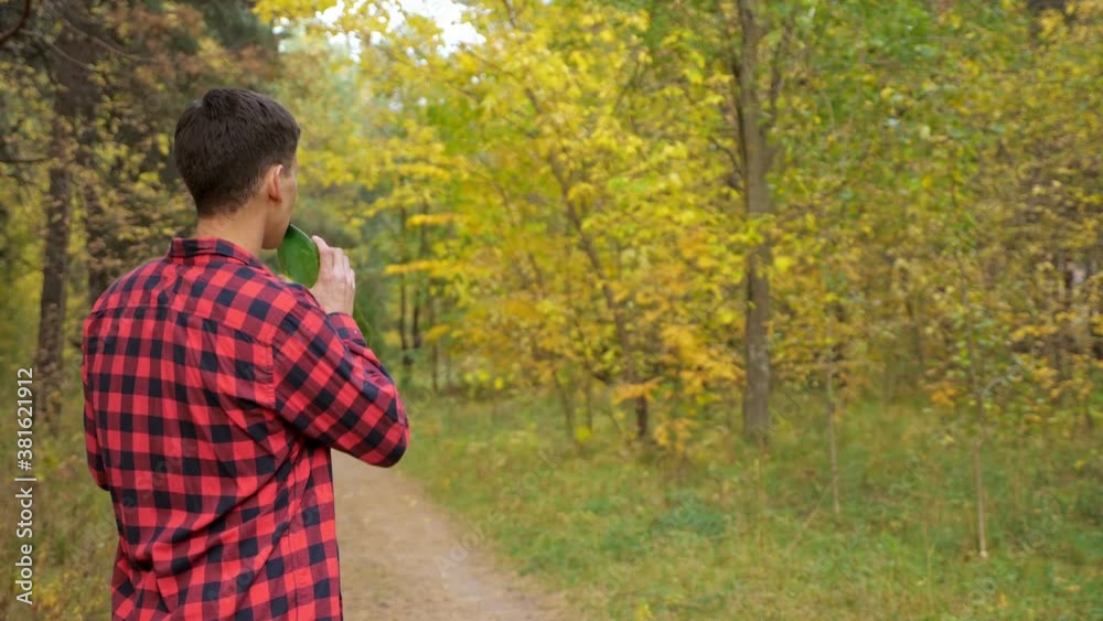 Man in a checkered shirt throws out a plastic bottle in the forest. Man in a checkered shirt throws out a plastic bottle in the forest.