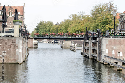 Gorinchem, the Netherlands, September 23, 2020: view along Linge river, lined with trees, and crossed by a bridge decorated with flowers photo