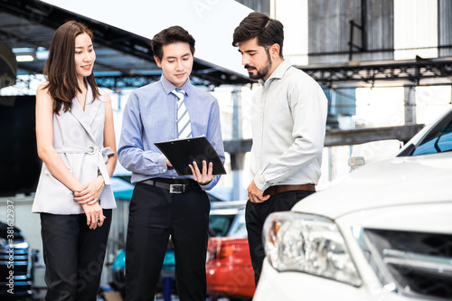 Car Dealership. The Asian Salesman (woman and man) checking the list with the middle east customer before hand over. Automotive Leasing and Dealing Business. International Business.