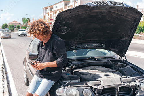 Young caucasian man trying to repair a breakdown in his car