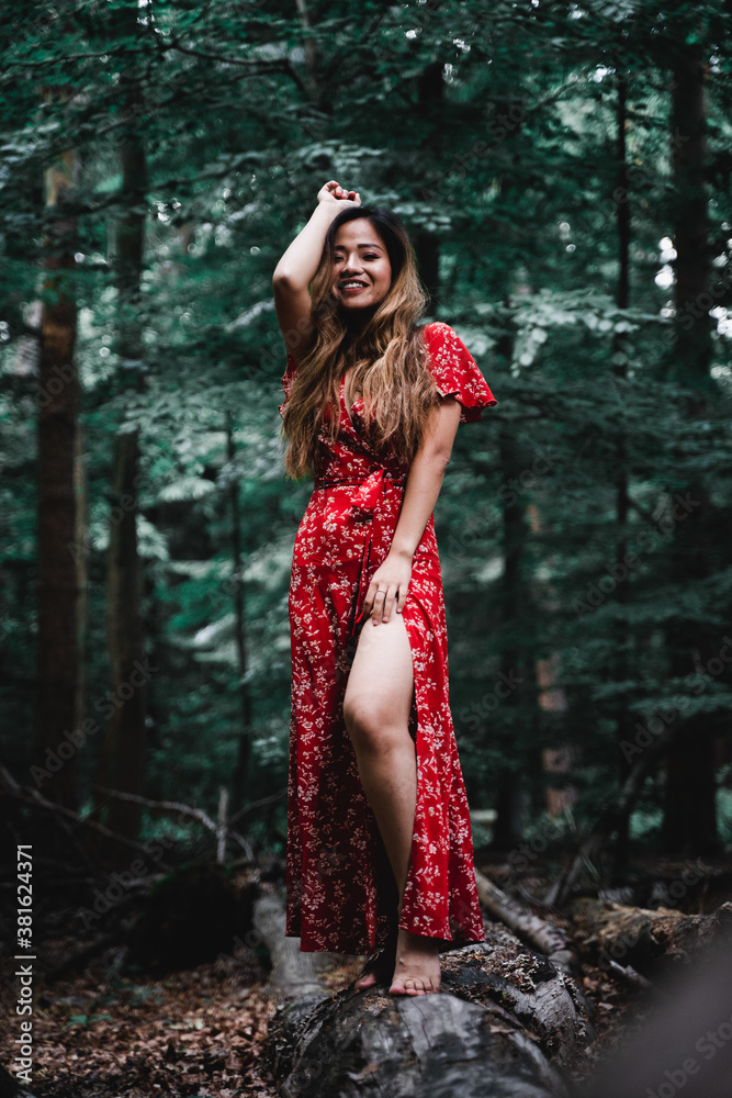 Beautiful Asian woman in red dress standing in a forest Beautiful Asian woman in red dress standing in a forest