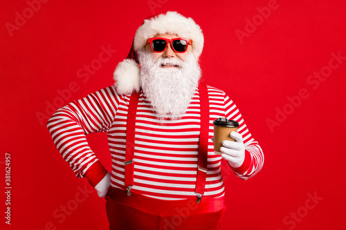 Portrait of his he nice handsome attractive cheerful cheery Santa father drinking takeout beverage cafe service isolated bright vivid shine vibrant red color background © deagreez