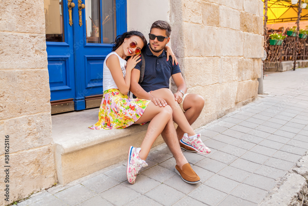 young beautiful hipster couple in love sitting on old city street, summer Europe vacation, travel, fun, happy, smiling
