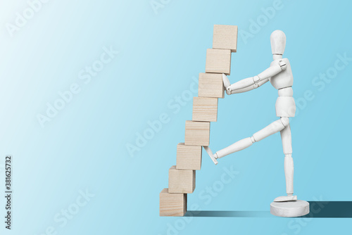 Mannequin with wooden cubes. Content completion concept. A mannequin on a blue pastel background is holding wooden empty cubes.