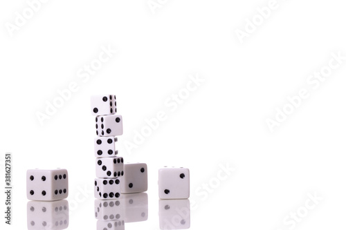 Stack of five white dice and Scattered dice of different sizes reflected in table surface isolated on white background copy space