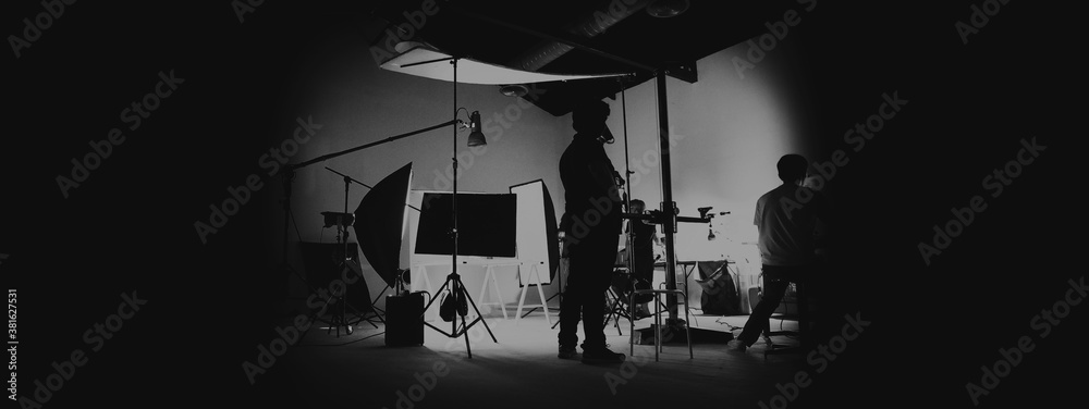Behind the scene of photo shooting and production set up in the big studio. Professional crew team working and camera equipment in silhouette. such as light box, tripod, flashlight. and copy space. - obrazy, fototapety, plakaty 