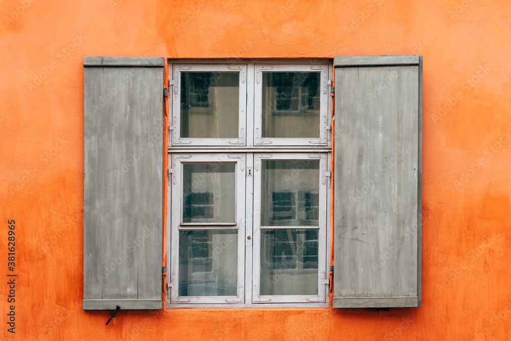 Old wooden window shutters of an european house with orange painted facade
