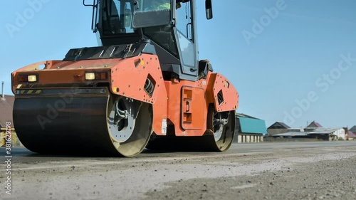 The roller levels and compacts the asphalt against the blue sky. A layer of freshly laid asphalt. Road roller. Road surface repair. Construction of a new road. Sunny day.