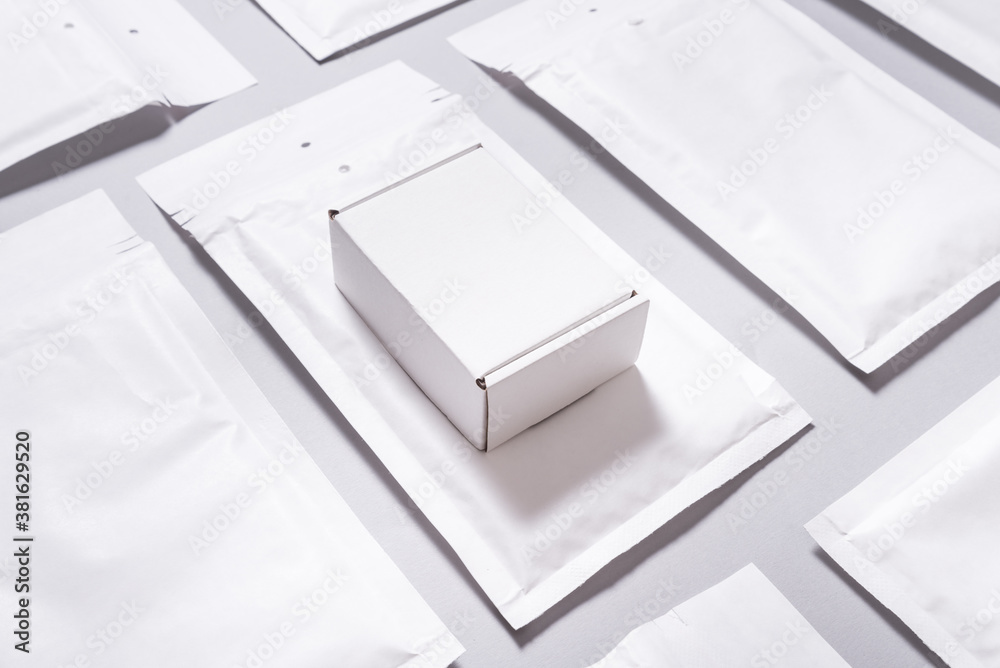 Lot of white paper bubble envelopes and carton box on grey background, textured background Lot of white paper bubble envelopes and carton box on grey background, textured background